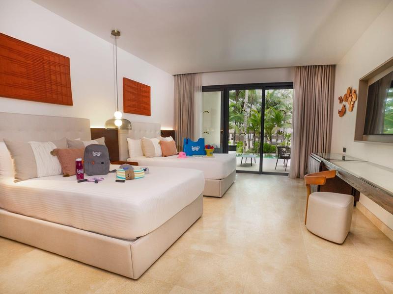 Camera d'hotel moderna con due letti grandi, balcone e vista sulla natura.