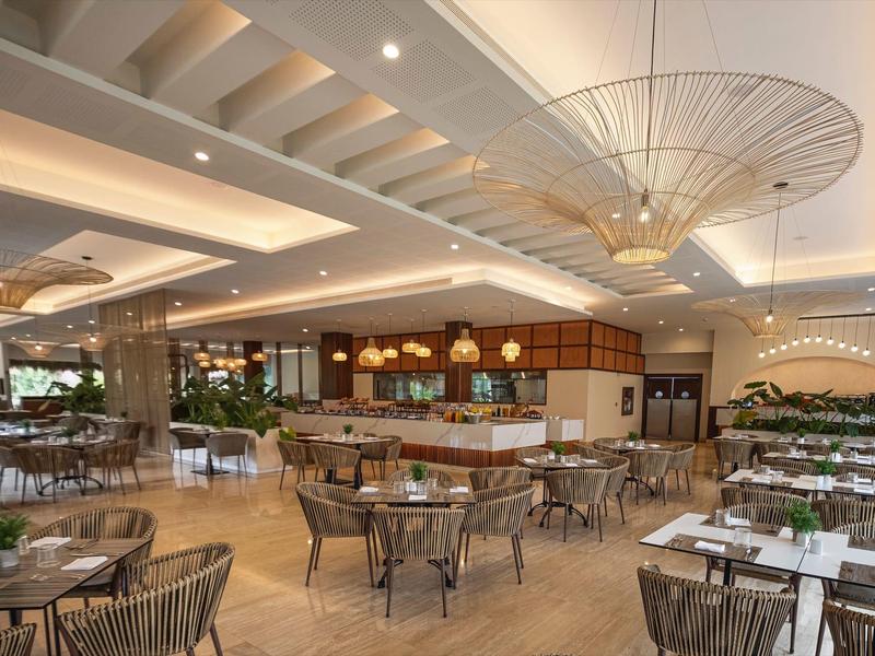 Ampia sala ristorante dell'hotel con design moderno e tavoli rotondi con sedie.