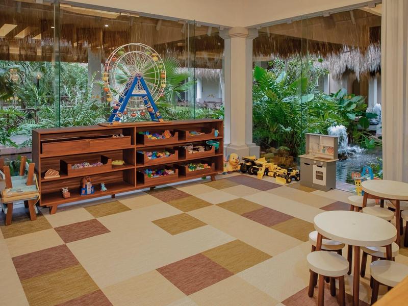 Terrazza coperta con scaffale in legno, posti a sedere e piante tropicali in un resort.