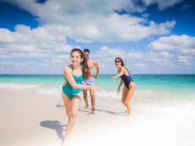 Tre persone in costume da bagno che giocano sulla spiaggia con il sole.