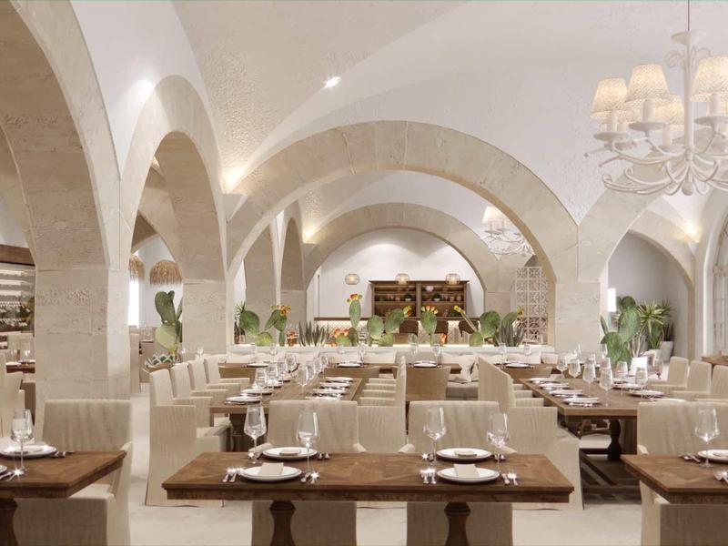 Elegantní restaurace s vysokými oblouky, bílými stěnami a stylově prostřenými stoly.