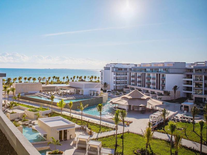 Moderní hotelový komplex s bazénem, slunečníky a terasou pod jasnou oblohou