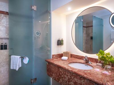 Bagno elegante con specchio rotondo, porta in vetro e piano lavabo in marmo.