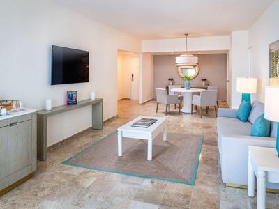 Soggiorno luminoso con divano, TV, tavolo e zona pranzo in stile moderno.