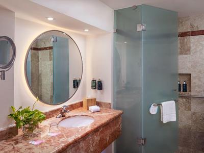 Bagno moderno con specchio rotondo, lavabo in marmo e cabina doccia in vetro.
