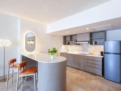 Area cucina moderna con banco bar, sgabelli e frigorifero in uno spazio luminoso e aperto.