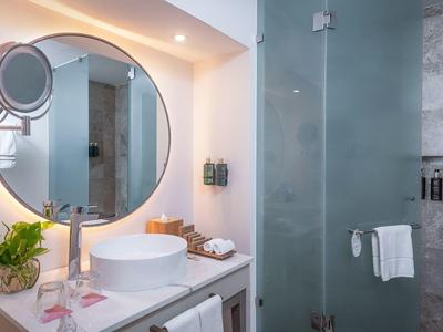 Bagno moderno con specchio rotondo illuminato, lavabo e porta doccia in vetro