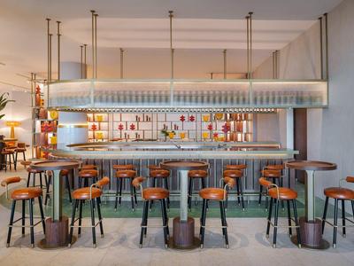 Area bar moderna con sgabelli in legno e bancone elegantemente illuminato.