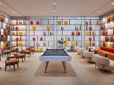 Moderner Gemeinschaftsraum mit Billardtisch, gemütlichen Sitzgelegenheiten und dekorativen Regalen.