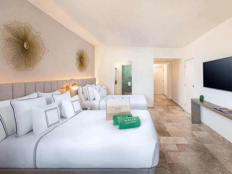 Camera d'hotel luminosa e moderna con letto grande, divano, TV e decorazioni minimaliste.