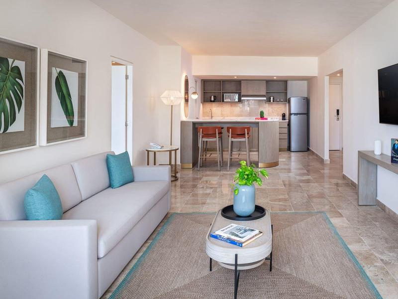 Soggiorno moderno con divano grigio, tavolino e cucina aperta sullo sfondo.