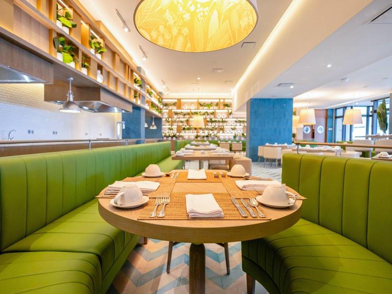 Ristorante moderno con panche imbottite verdi e tavolo rotondo in legno.