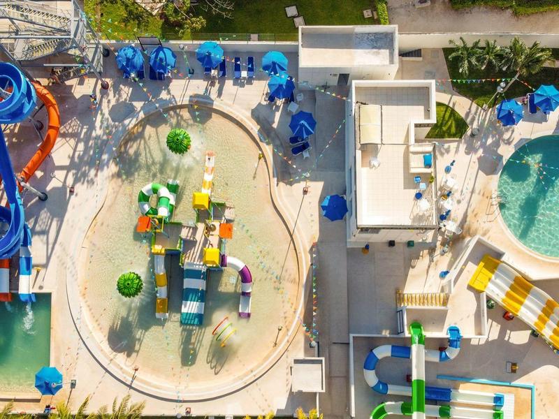 Vista aerea di un parco acquatico con scivoli d'acqua, piscina a spruzzo e area giochi.