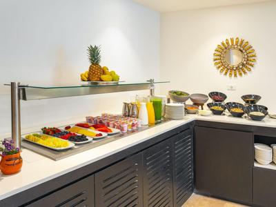 Buffet con fruta fresca, jugos y cuencos en una cocina de hotel moderna.