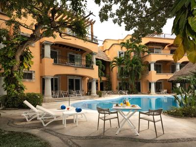 Hotel con piscina, tumbonas y mesa con bebidas en un entorno tropical.