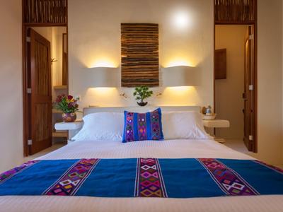 Modernes Hotelzimmer mit großem Bett und farbigem Dekokissen, warm beleuchtet.