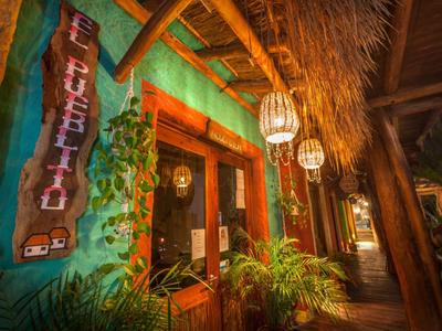 Gemütlicher, tropischer Hotel-Eingang mit leuchtenden Lampen und Pflanzen bei Nacht.