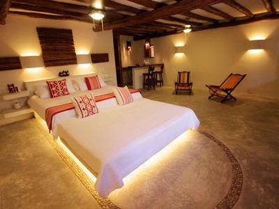 Gemütliches Schlafzimmer mit großem Bett, Sitzgelegenheiten und sanfter Beleuchtung.