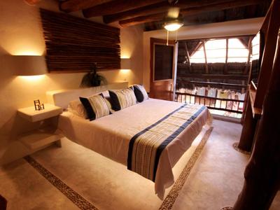 Gemütliches Schlafzimmer mit großem Bett, Holzbalkendecke und Balkon mit Blick nach draußen.