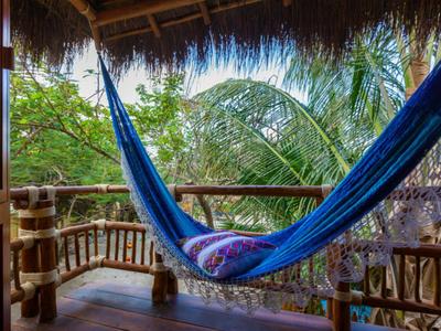 Blauer Hängematte auf Holzveranda mit tropischem Grün im Hintergrund