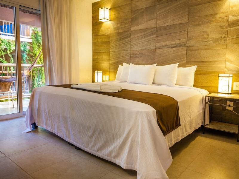 Camera d'hotel accogliente con letto grande, parete in legno e accesso alla terrazza.