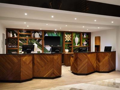 Hotelrezeption mit dunklen Holztheken und modernen Computern in einem gut beleuchteten Raum.