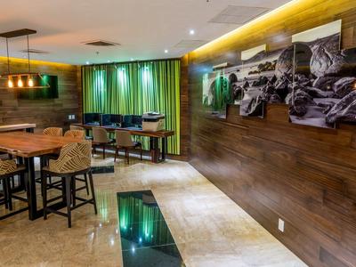 Salle de petit-déjeuner moderne avec murs en bois, tables, chaises et rideaux verts.