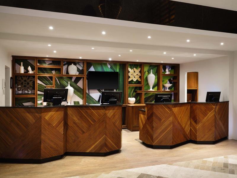 Comptoirs d'enregistrement modernes d'hôtel avec façades en bois et étagères décoratives en arrière-plan.