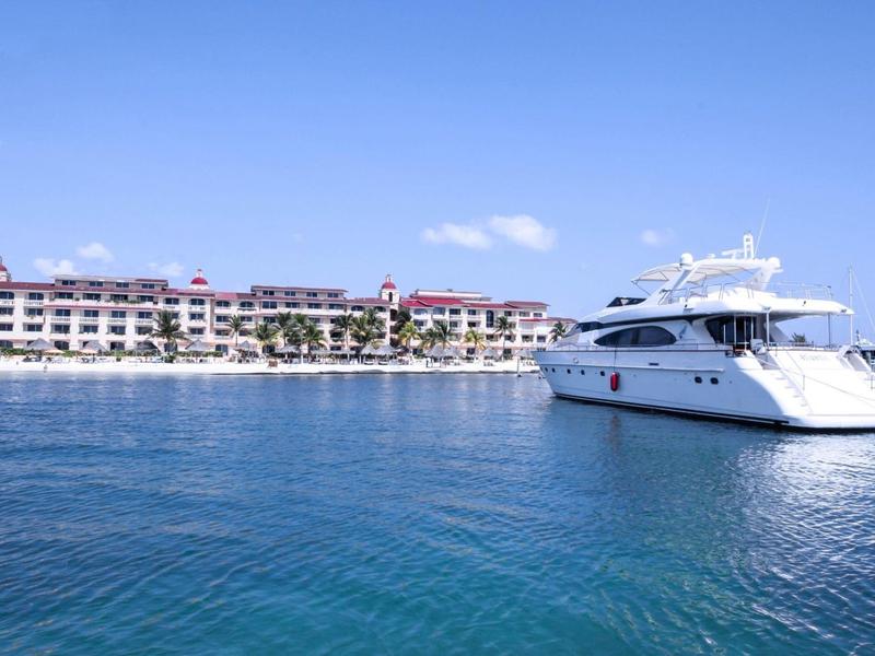 Yacht devant un grand hôtel sur une mer bleue calme sous un ciel clair.