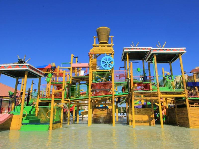 Aire de jeux aquatique colorée avec toboggans et bassin d'eau sous un ciel clair.