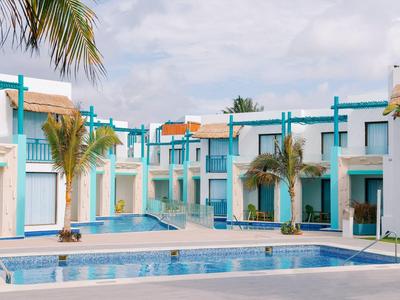 Complesso alberghiero moderno con piscina e palme sotto un cielo nuvoloso.