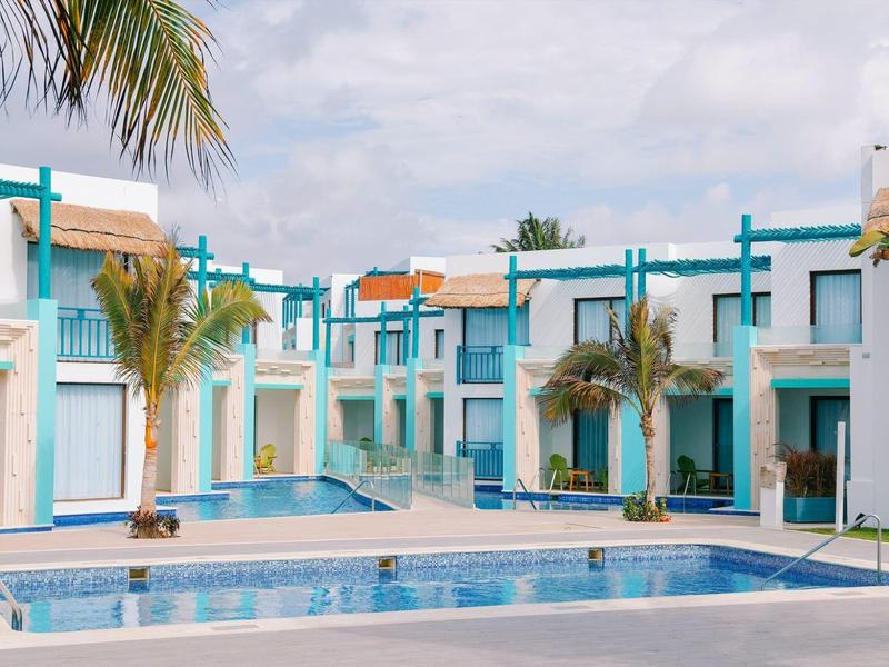Complesso alberghiero moderno con edifici blu e bianchi e piscine tra palme.