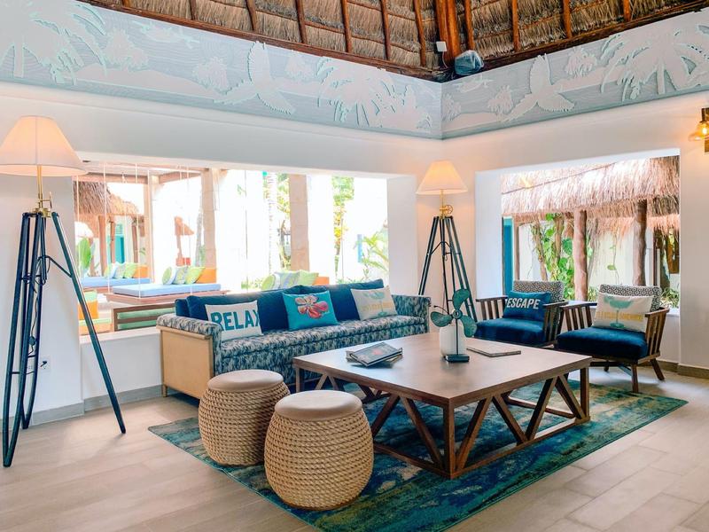 Soggiorno luminoso con divano, poltrone e tappeto sotto un tetto in legno aperto in hotel