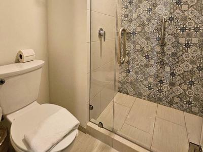 Mała łazienka z toaletą i prysznicem z ozdobną ścianą z płytek.