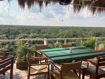 Terrasse mit grünem Billardtisch und Holzmöbeln, Blick auf grünen Wald im Hintergrund.