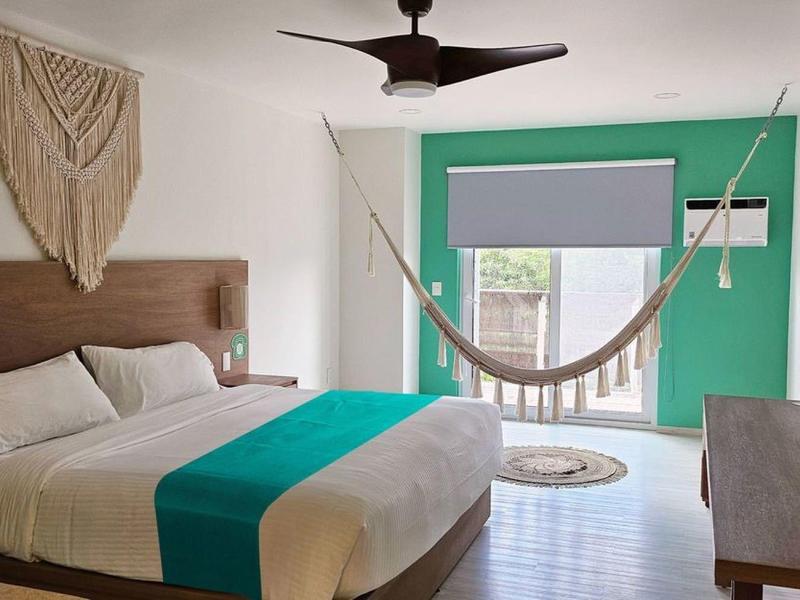 Sypialnia z łóżkiem king-size, hamakiem i turkusową ścianą akcentową.