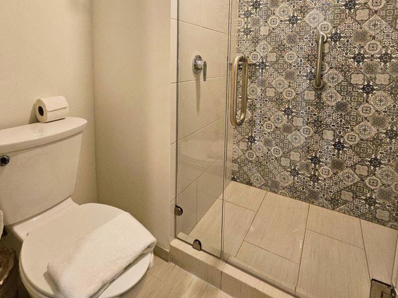 Mała łazienka z toaletą i prysznicem z ozdobną ścianą z płytek.