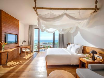 Modernes Hotelzimmer mit Blick auf das Meer, gemütlichem Bett und Holzmöbeln.