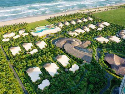 Luftaufnahme eines weitläufigen Resorts mit weißen Gebäuden, Pool und grüner Umgebung.