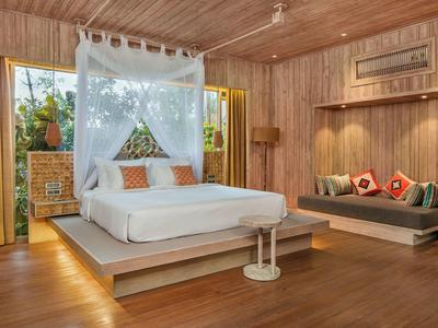 Przestronna drewniana sypialnia z dużym łóżkiem, sofą i dużą ilością naturalnego światła z dużych okien.