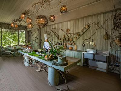 Rustikaler Speisebereich im Freien mit großer Tafel, Pflanzen und natürlichen Dekorationen.