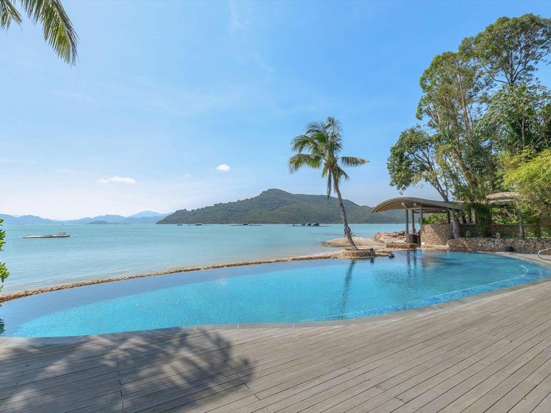 Basen infinity z widokiem na morze i palmy pod błękitnym niebem.