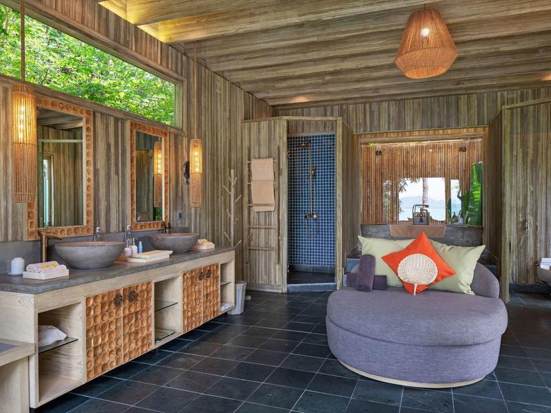 Rustykalna łazienka z drewnianą boazerią, nowoczesną wanną i dużym lustrem.