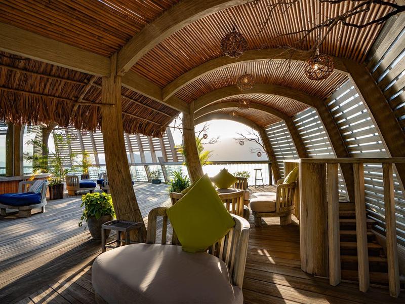 Jasna i przytulna przestrzeń do siedzenia na plaży z drewnianym dachem i widokiem na morze.