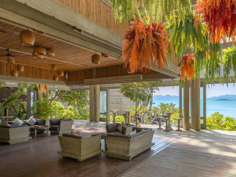 Otwarta strefa wypoczynkowa hotelu z wygodnymi fotelami i widokiem na morze.