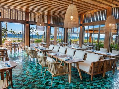 Modernes Restaurant mit Sitzgelegenheiten und Blick auf das Wasser durch große Fenster.