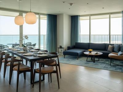 Moderner Wohn- und Essbereich mit Holzboden, großem Fenster, dunklem Sofa, Esstisch und Stühlen.