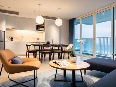 Moderner Wohnraum mit braunem Sessel, rundem Holztisch, Essbereich und großem Glasfenster zum Balkon.