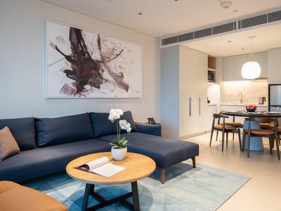 Modernes Wohnzimmer mit dunkelblauem Ecksofa, rundem Holztisch und abstraktem Bild an der Wand.