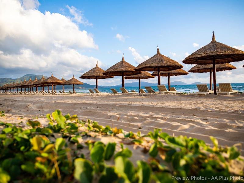 Reihe von Strohdächern am Strand mit Blick auf das Meer und bewölkten Himmel